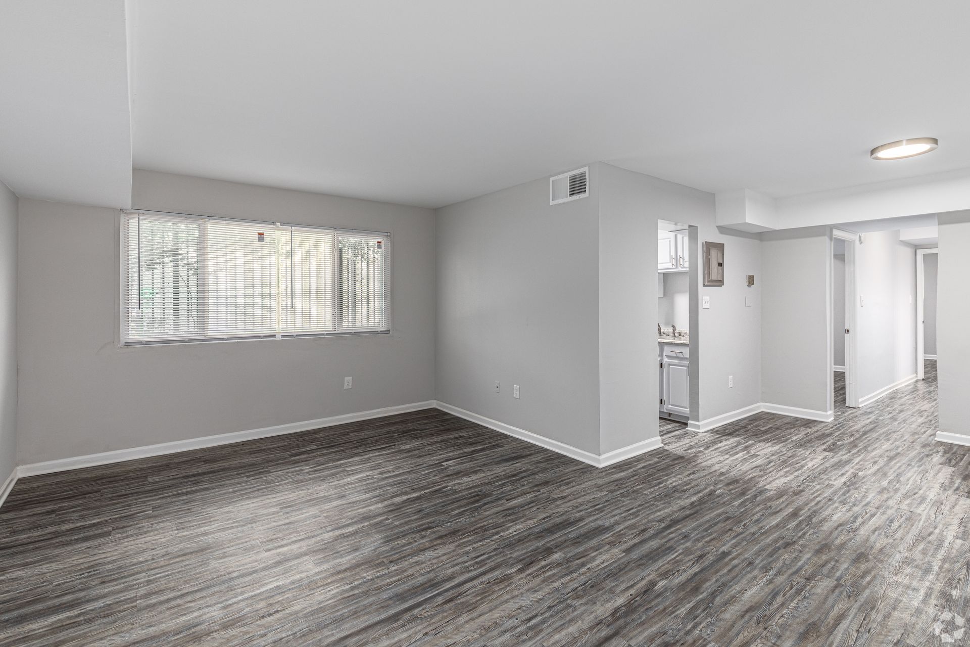 An empty living room with hardwood floors and a large window.