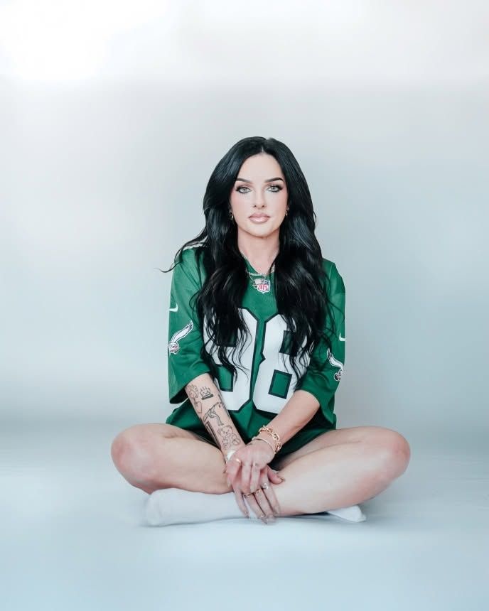woman sitting on ground wearing green football jersey