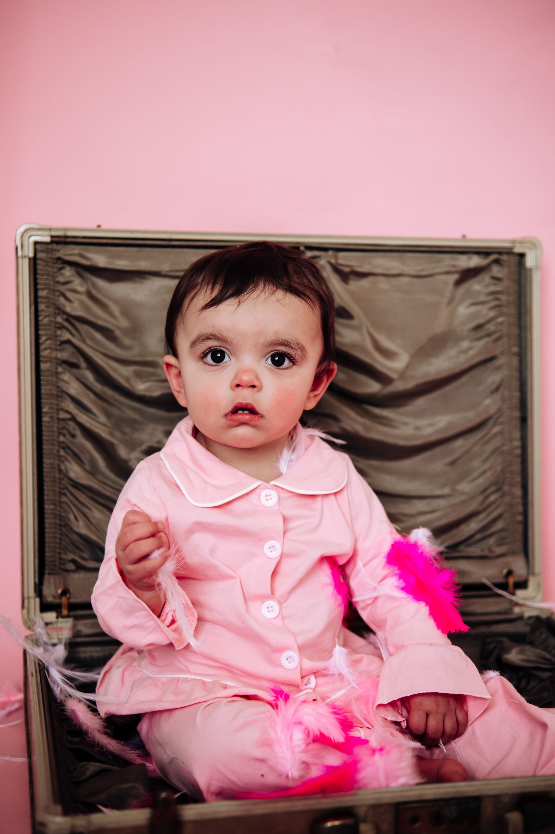 baby girl sitting in suitcase