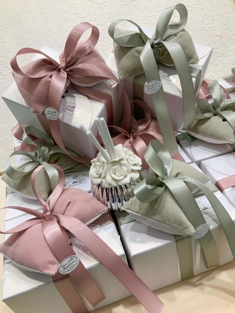 Scatole regalo rosa pastello e verdi, legate con nastri e disposte in una pila festosa.