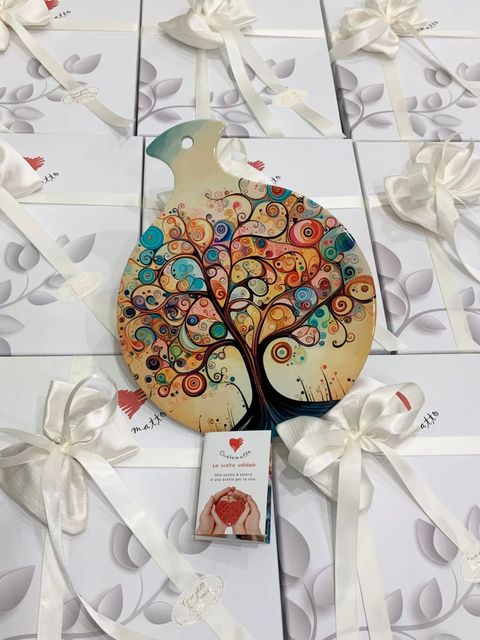 Sagoma decorativa in legno di un albero con una corona colorata a forma di cuore su sfondo di nastro bianco.