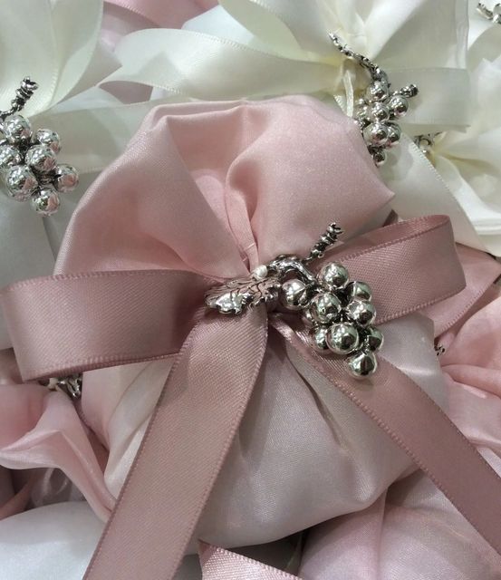 Fiocco in raso rosa pallido con spille di strass argentati su un delicato sfondo floreale bianco.