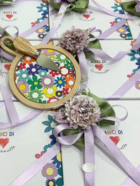 Una tavolozza di fiori e un bouquet avvolto in un nastro, su fogli di carta con il logo del marchio, con fiori viola.