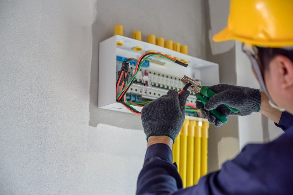 An electrician is working on an electrical box in a room.