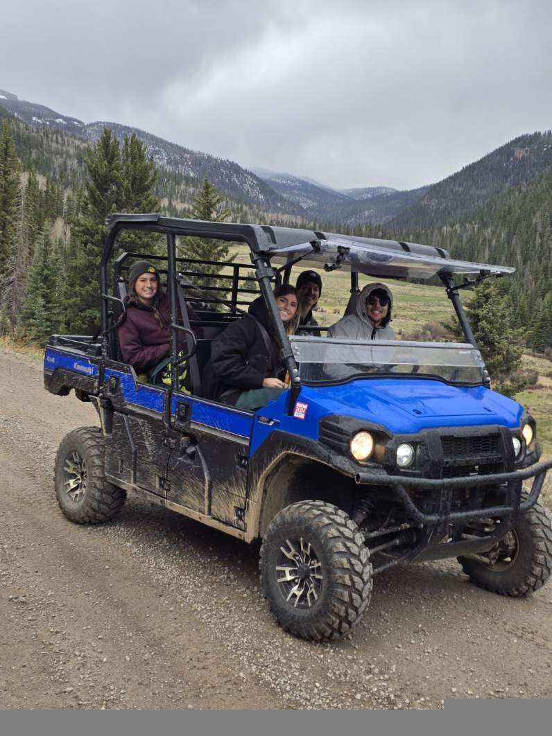 A group of people are riding in a blue atv on a dirt road.