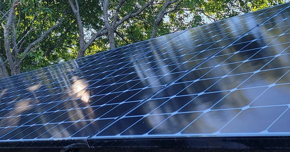 A close up of a solar panel on a roof with trees in the background.
