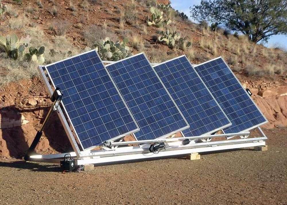 A row of solar panels sitting on top of a dirt field