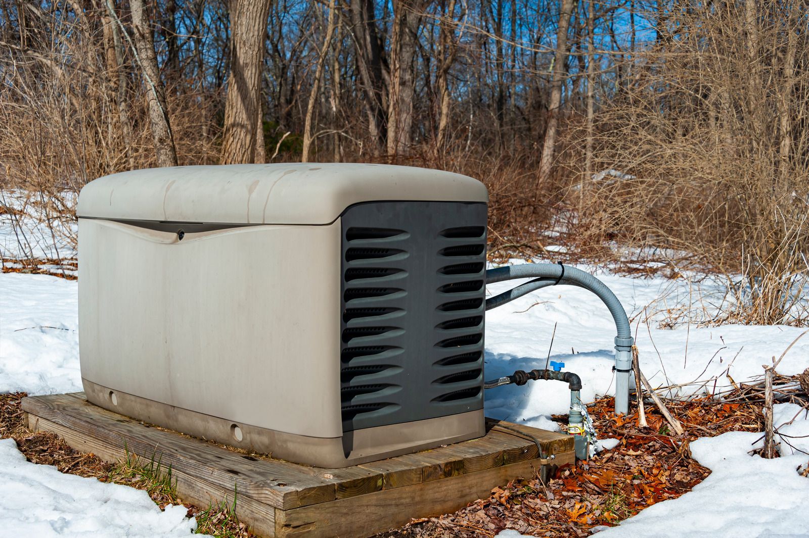A generator is sitting in the snow in the middle of a forest.