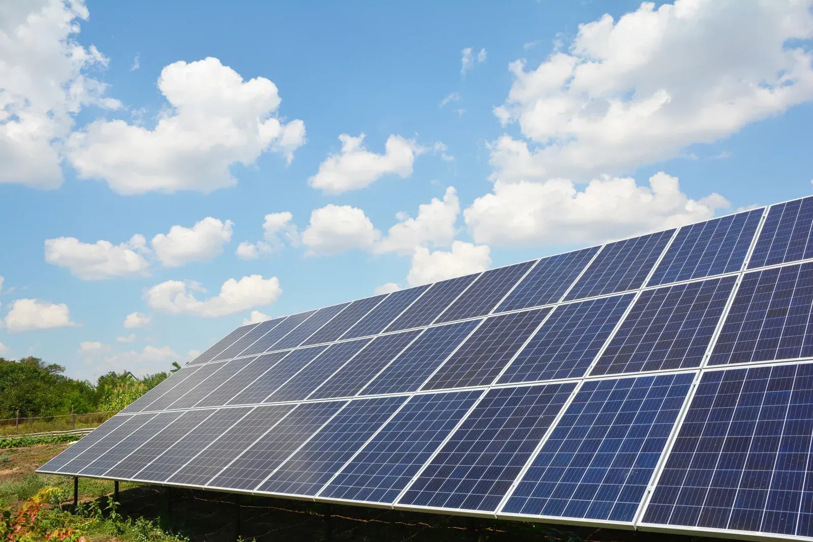 A row of solar panels against a blue sky with clouds