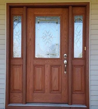 Wooden front door with sidelights; frosted glass design, brown trim, and silver hardware.