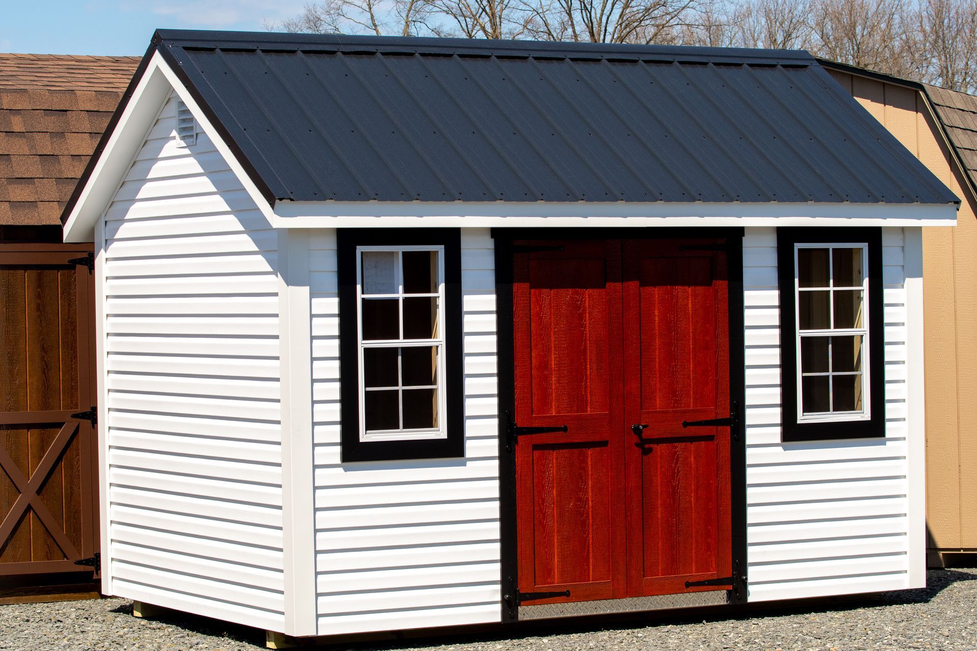 A white shed with a red door and windows