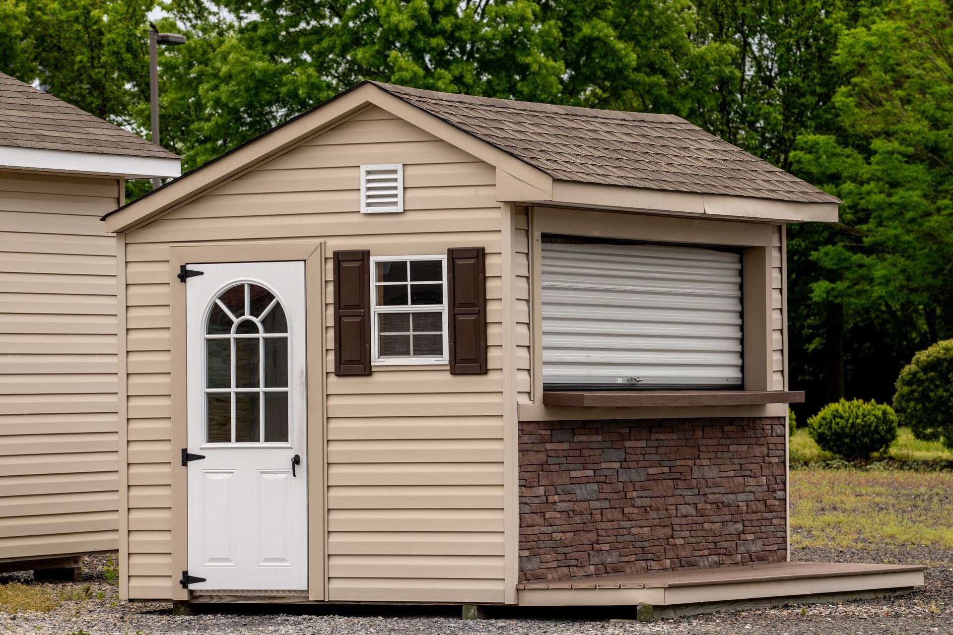 A small shed with a window and shutters on the side of it.