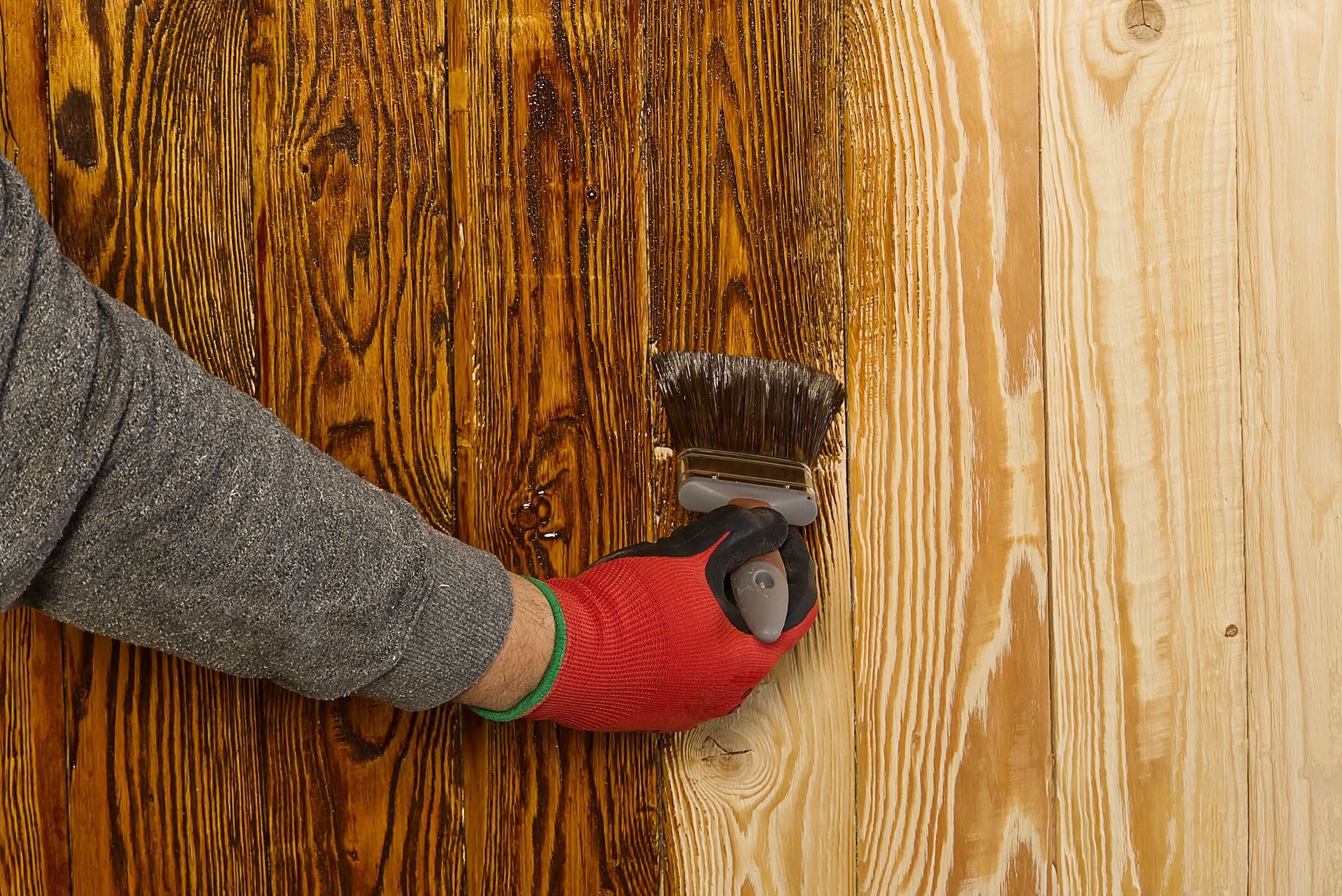 A person is painting a wooden surface with a brush.
