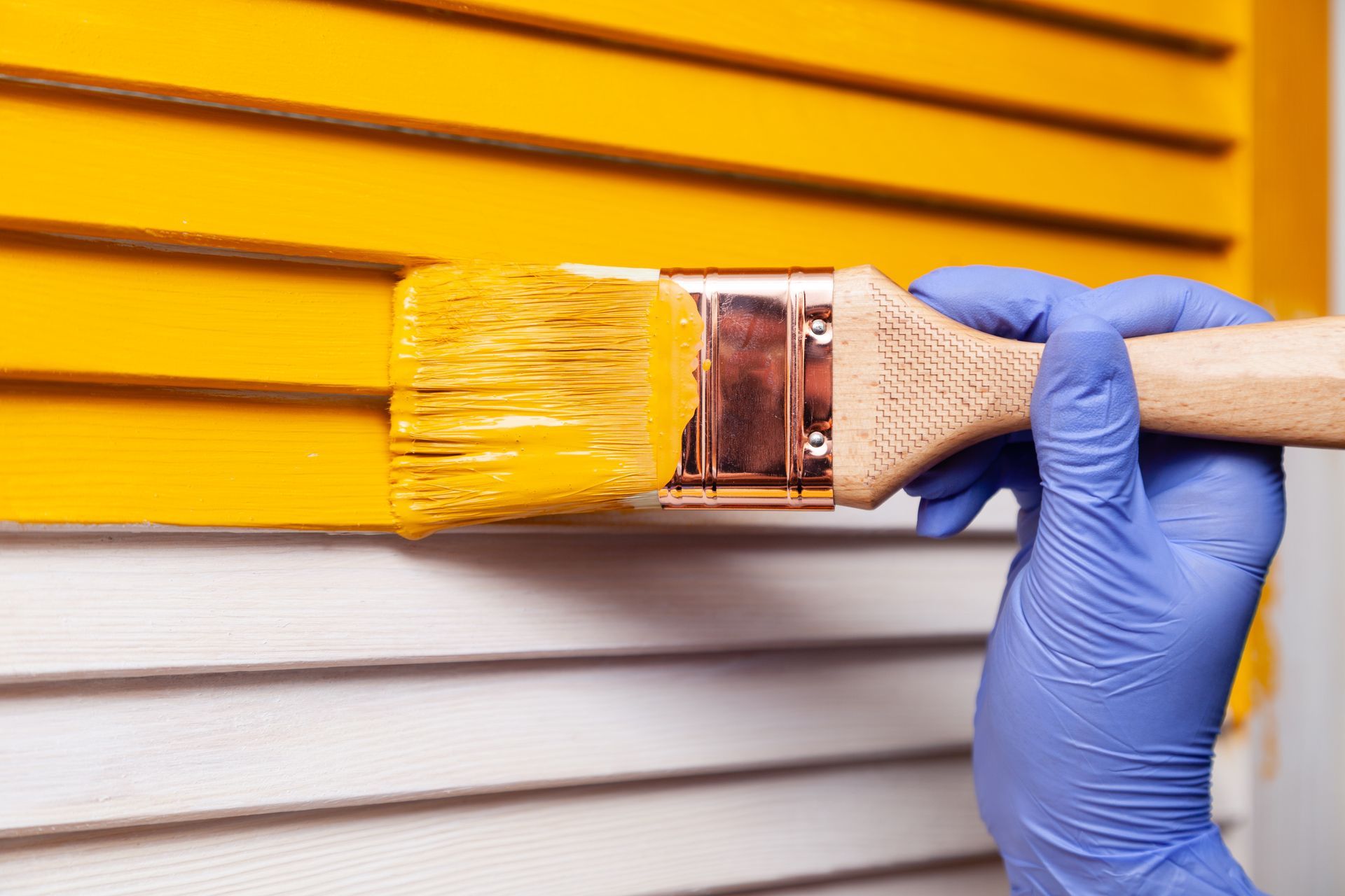 A person is painting a yellow wall with a brush.
