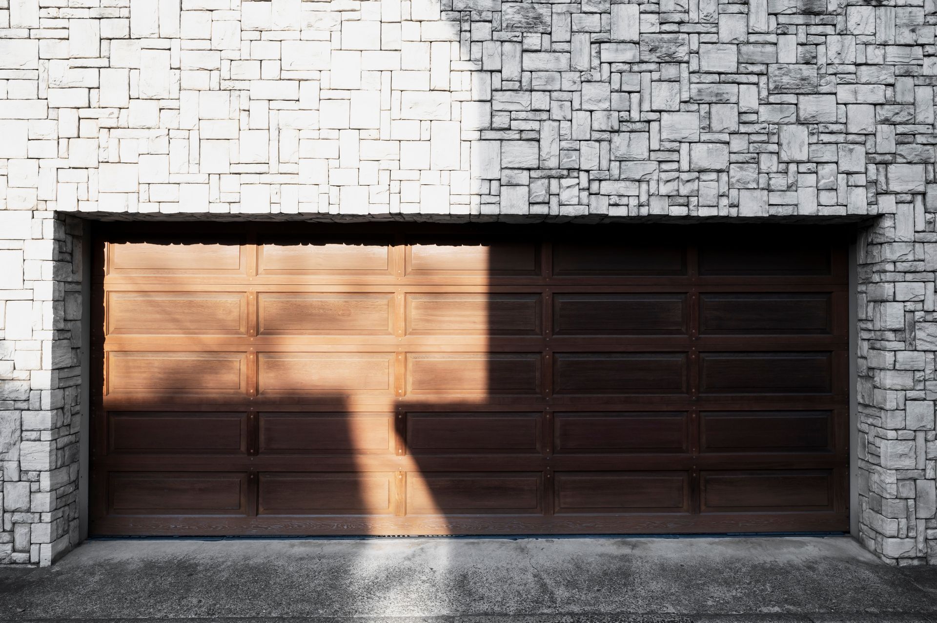 A wooden garage door with a stone wall behind it