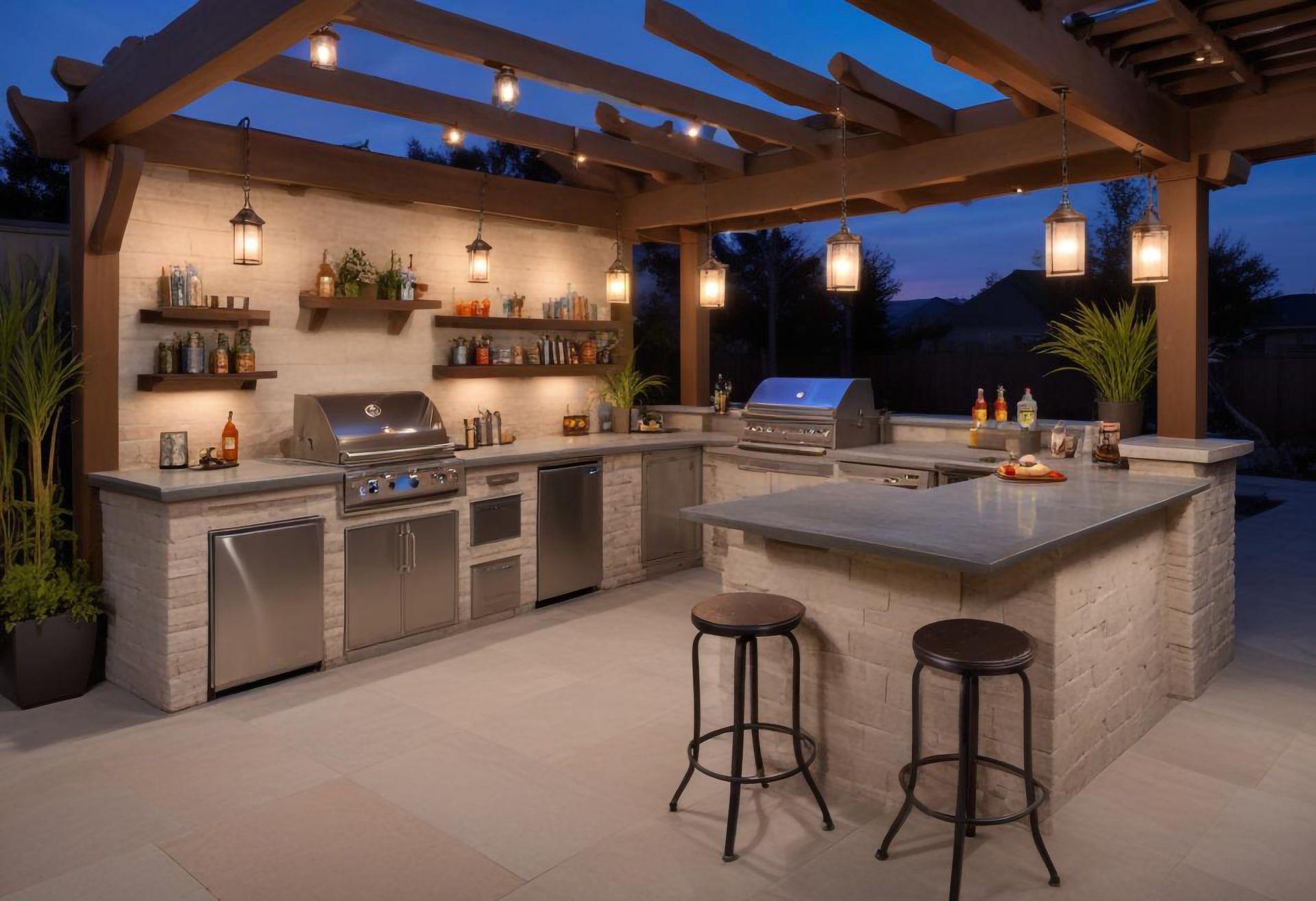 An outdoor kitchen with stools and a grill under a pergola at night.