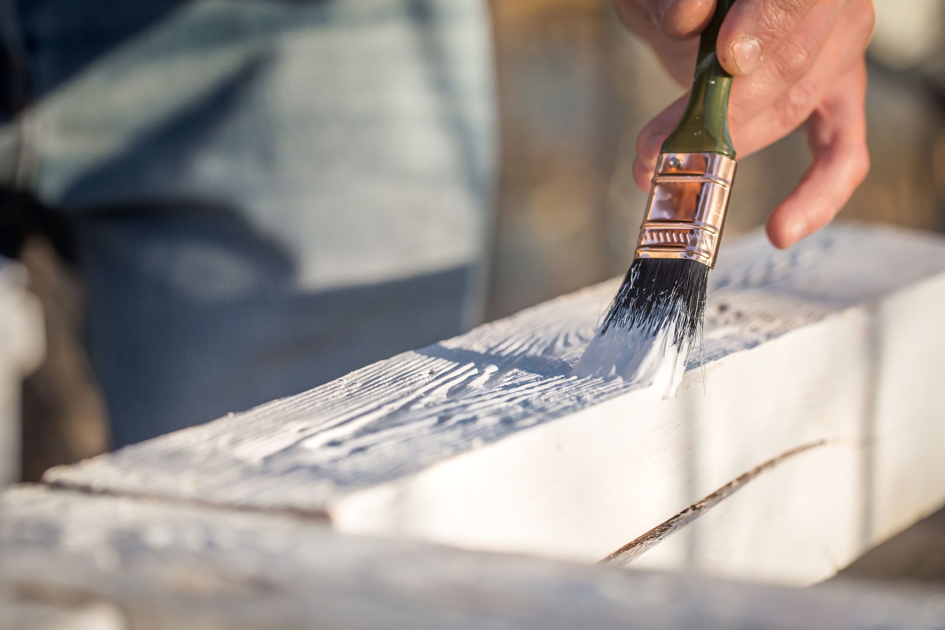 A person is painting a piece of wood with a brush.