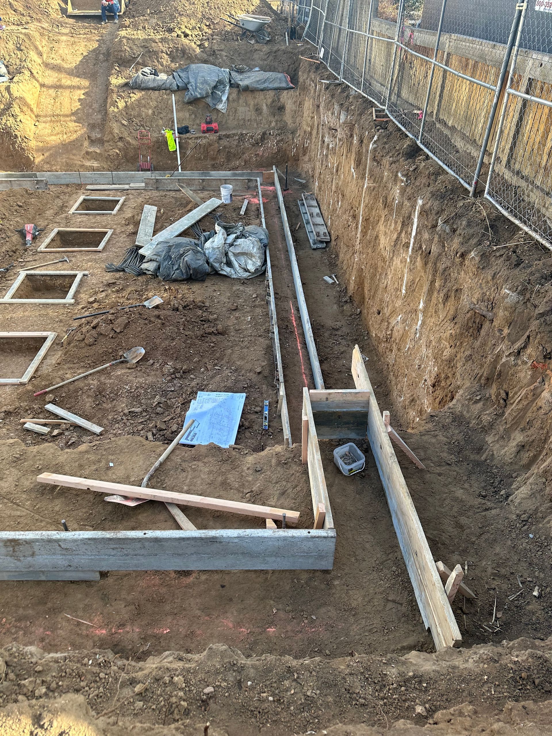A construction site with a lot of dirt and a fence in the background.