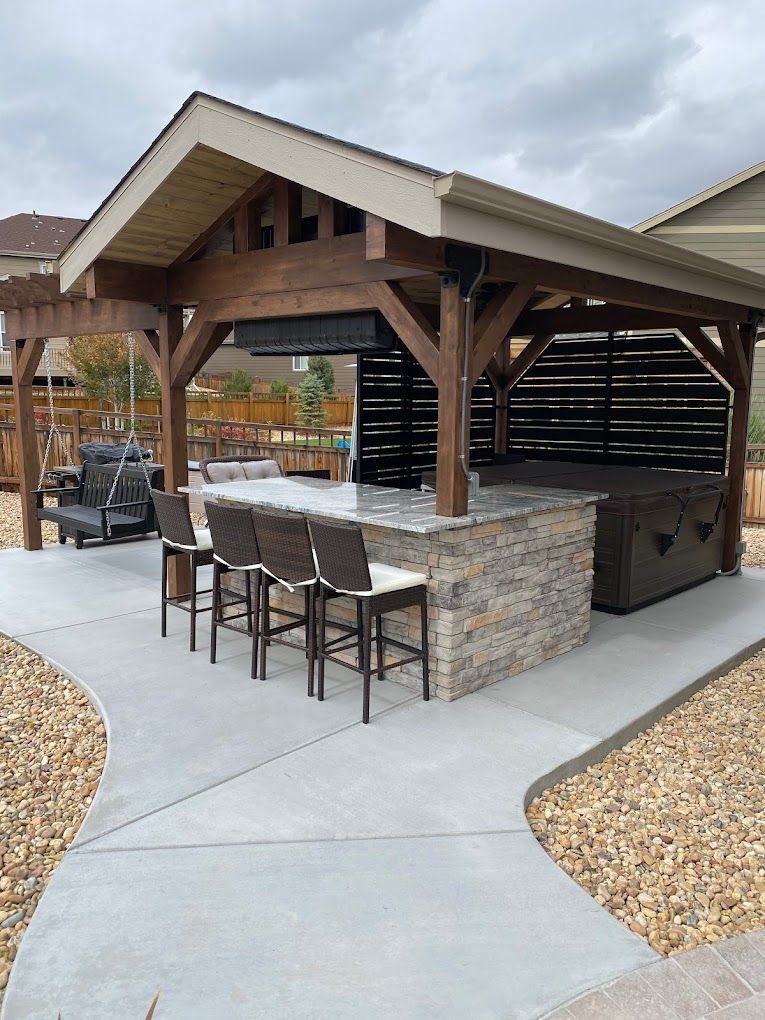 A gazebo with a bar and chairs underneath it.