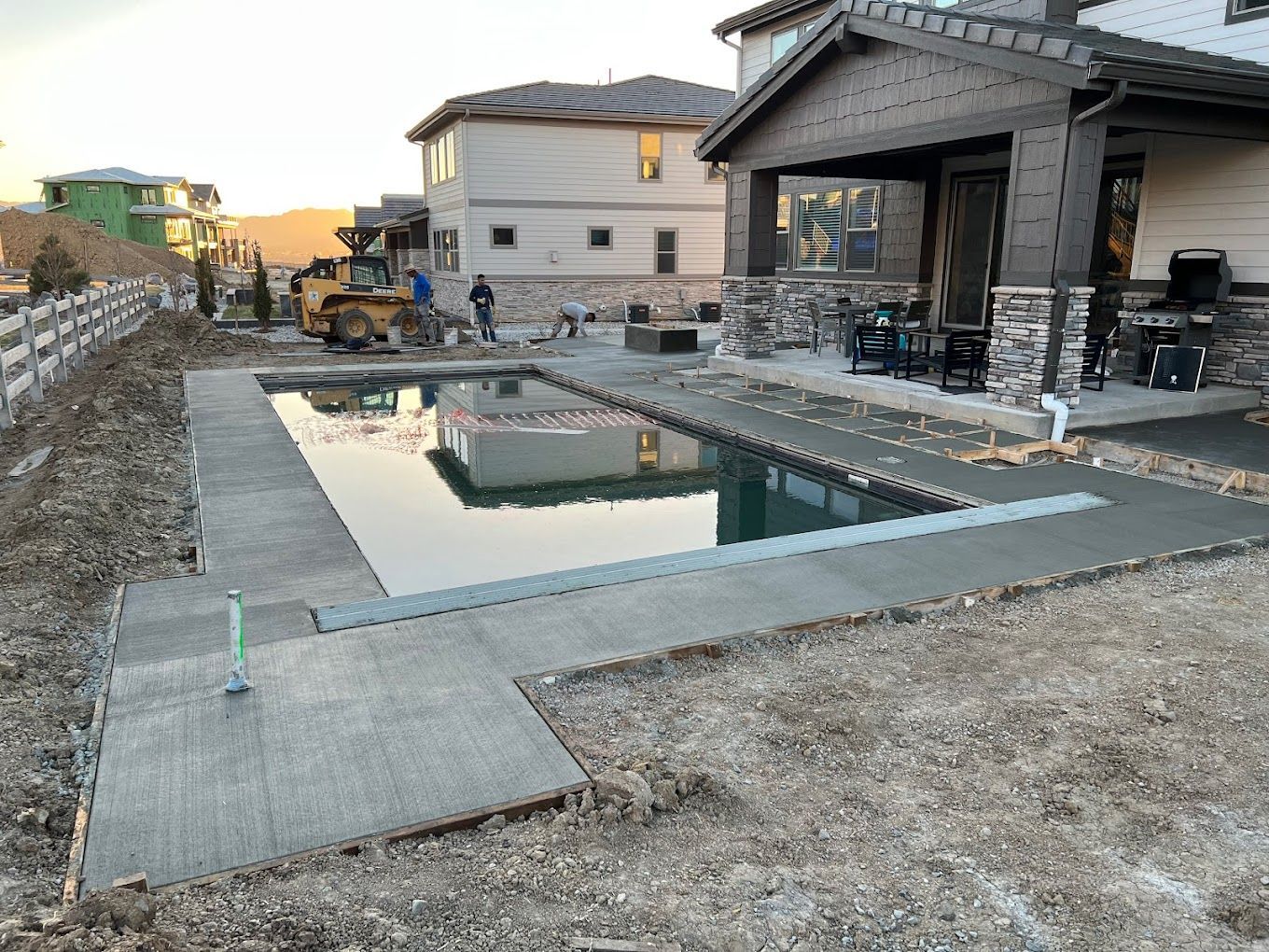 A large swimming pool is being built in the backyard of a house.