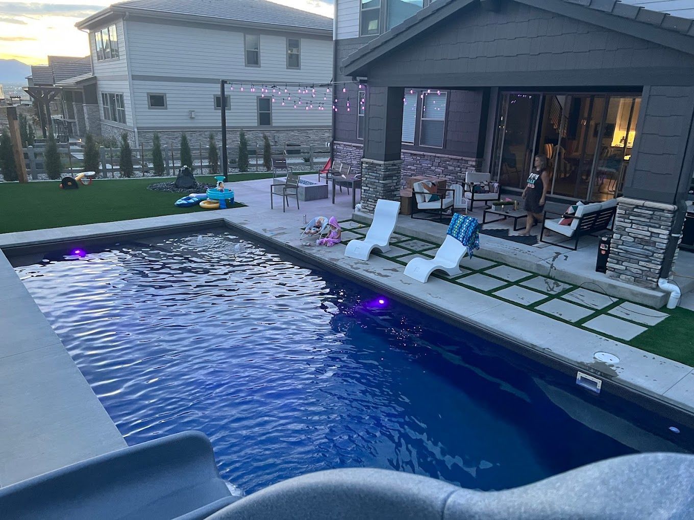 There is a large swimming pool in the backyard of a house.