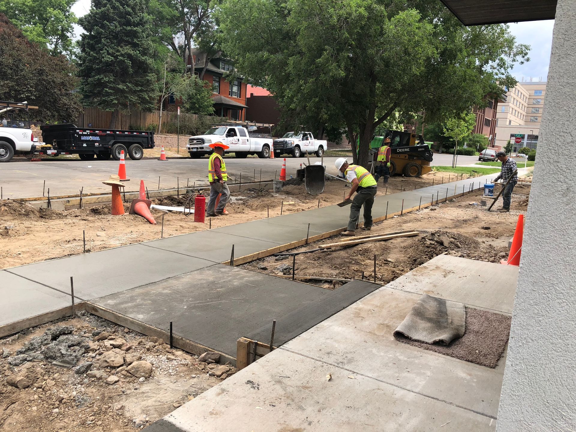 A group of construction workers are working on a sidewalk.