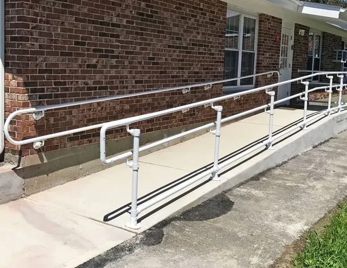 A ramp with a white railing is leading to a brick building.
