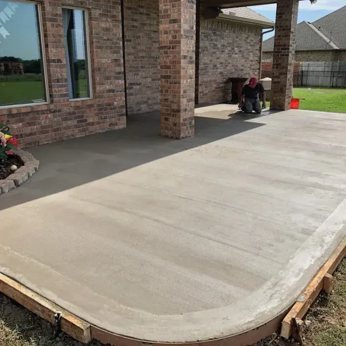 A concrete patio is being built in front of a brick house.
