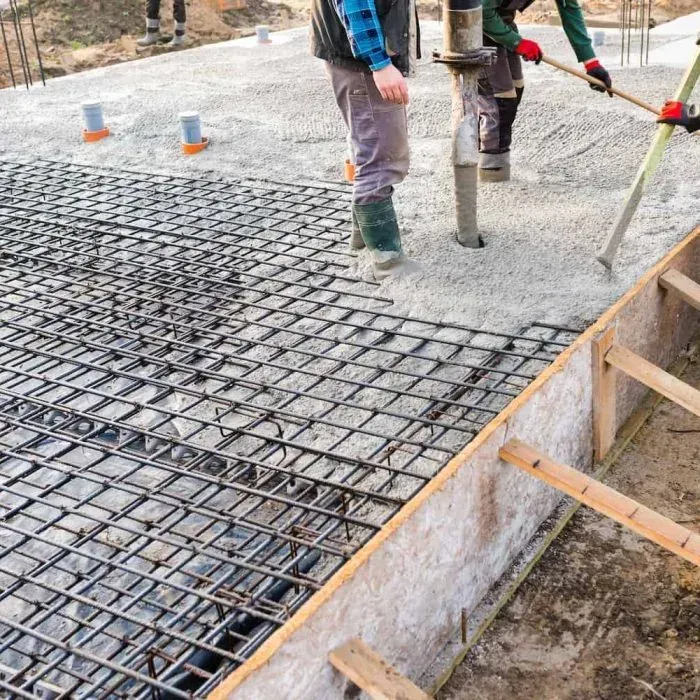 A man is pouring concrete into a foundation at a construction site.