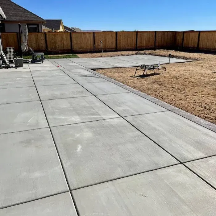 A large concrete patio with a wooden fence in the background.