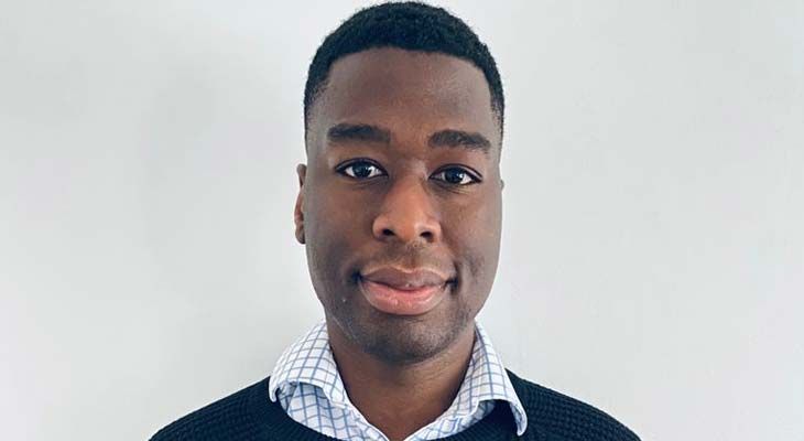 Portrait of a person in a dark sweater and checkered shirt against a plain white background
