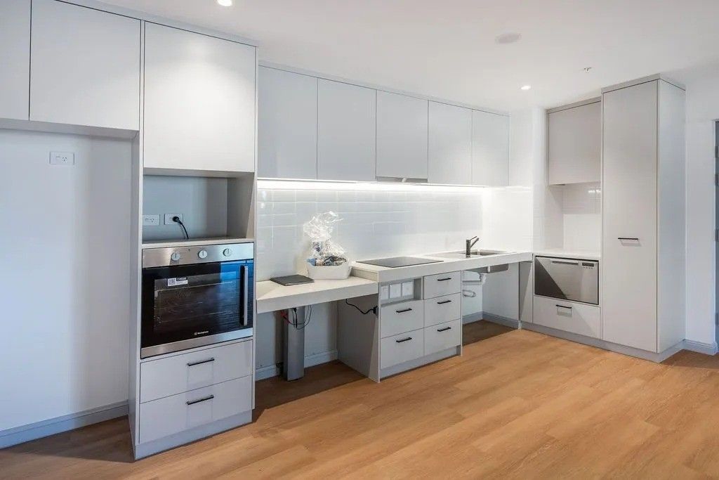 Modern, accessible kitchen with white cabinets, stainless steel appliances, and wood flooring.
