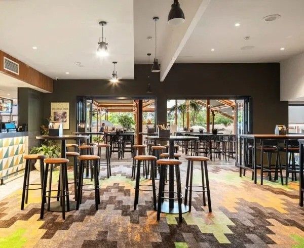Interior of a modern bar with high tables, stools, and open doors to an outdoor area.
