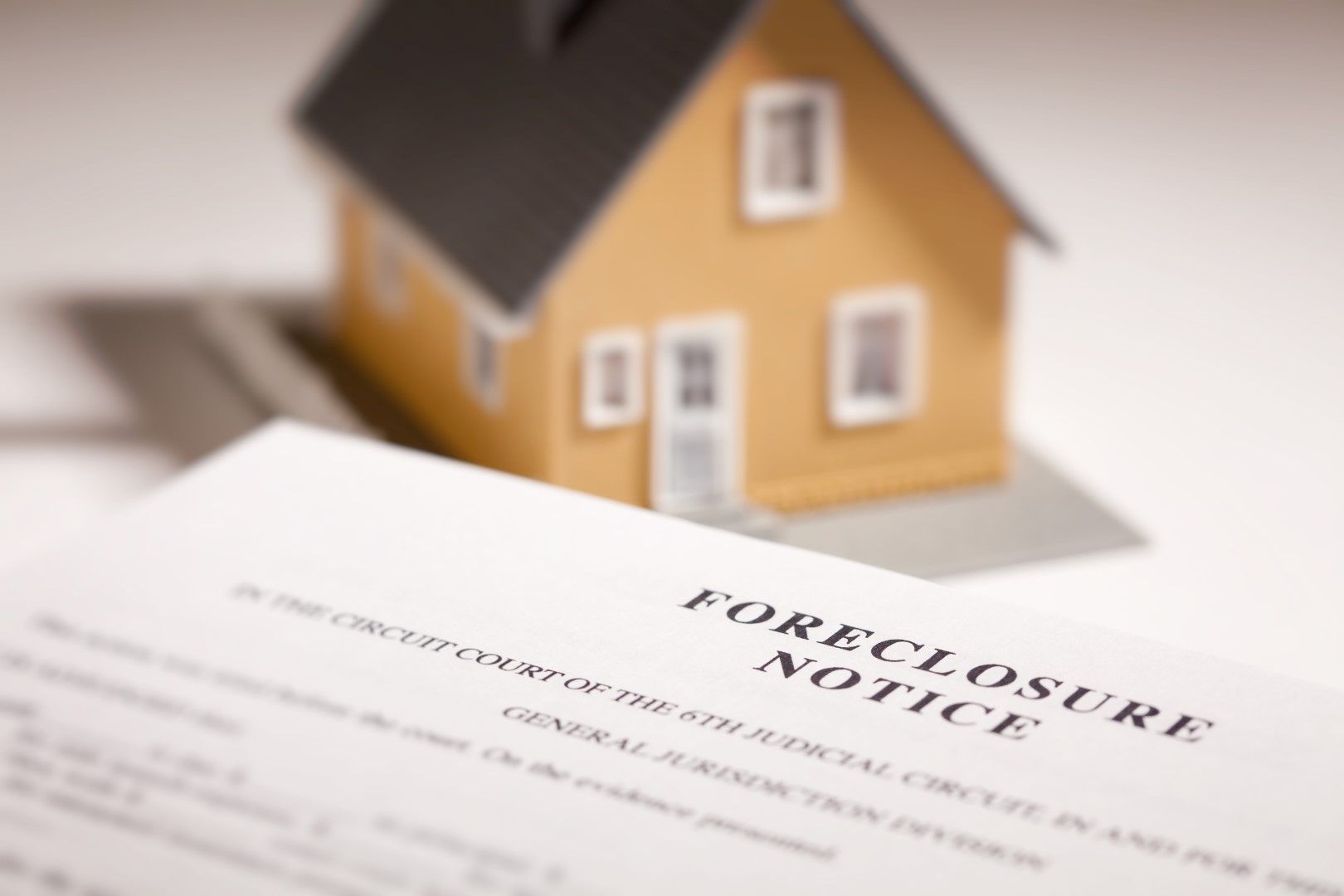 Foreclosure notice beside a small house model
