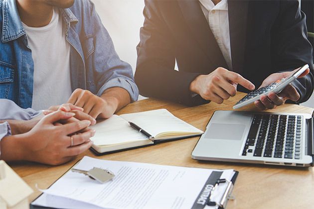 People reviewing documents at a table with a laptop and notebook in a bright office meeting