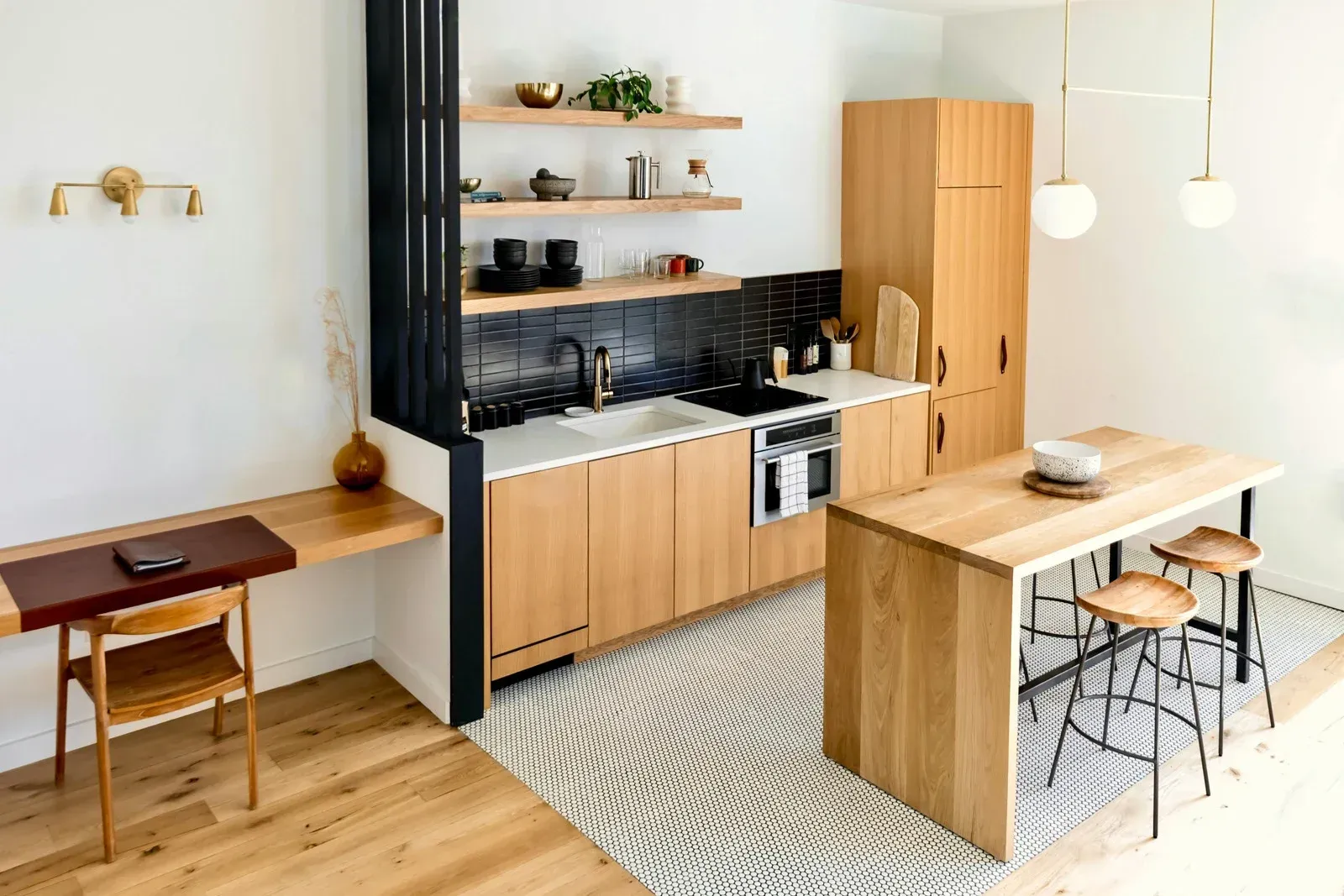 Bright modern kitchen and dining nook with wood cabinets, island, stools, and desk by a window