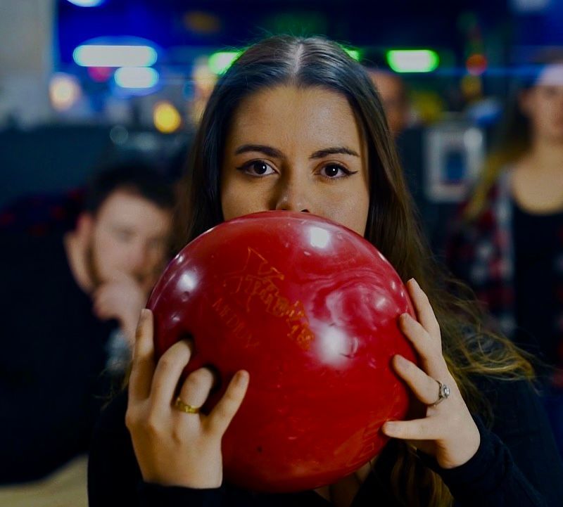 Person holding a shiny red bowling ball in a dim bowling alley — Orange Tenpin Bowl in Orange, NSW