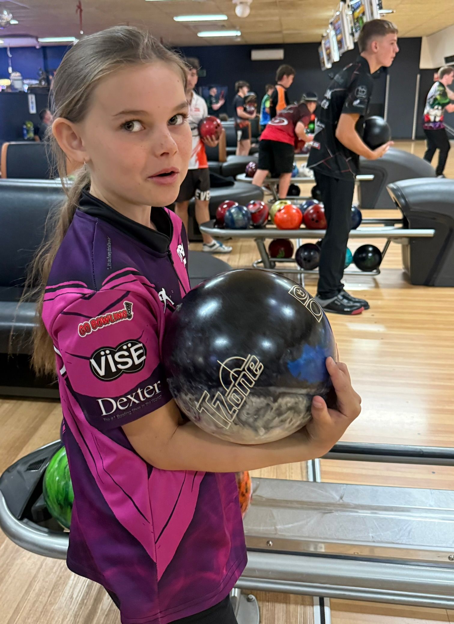 Young Bowler in a Purple Jersey Holding a Black Bowling Ball at a Bowling Alley — Orange Tenpin Bowl in Orange, NSW