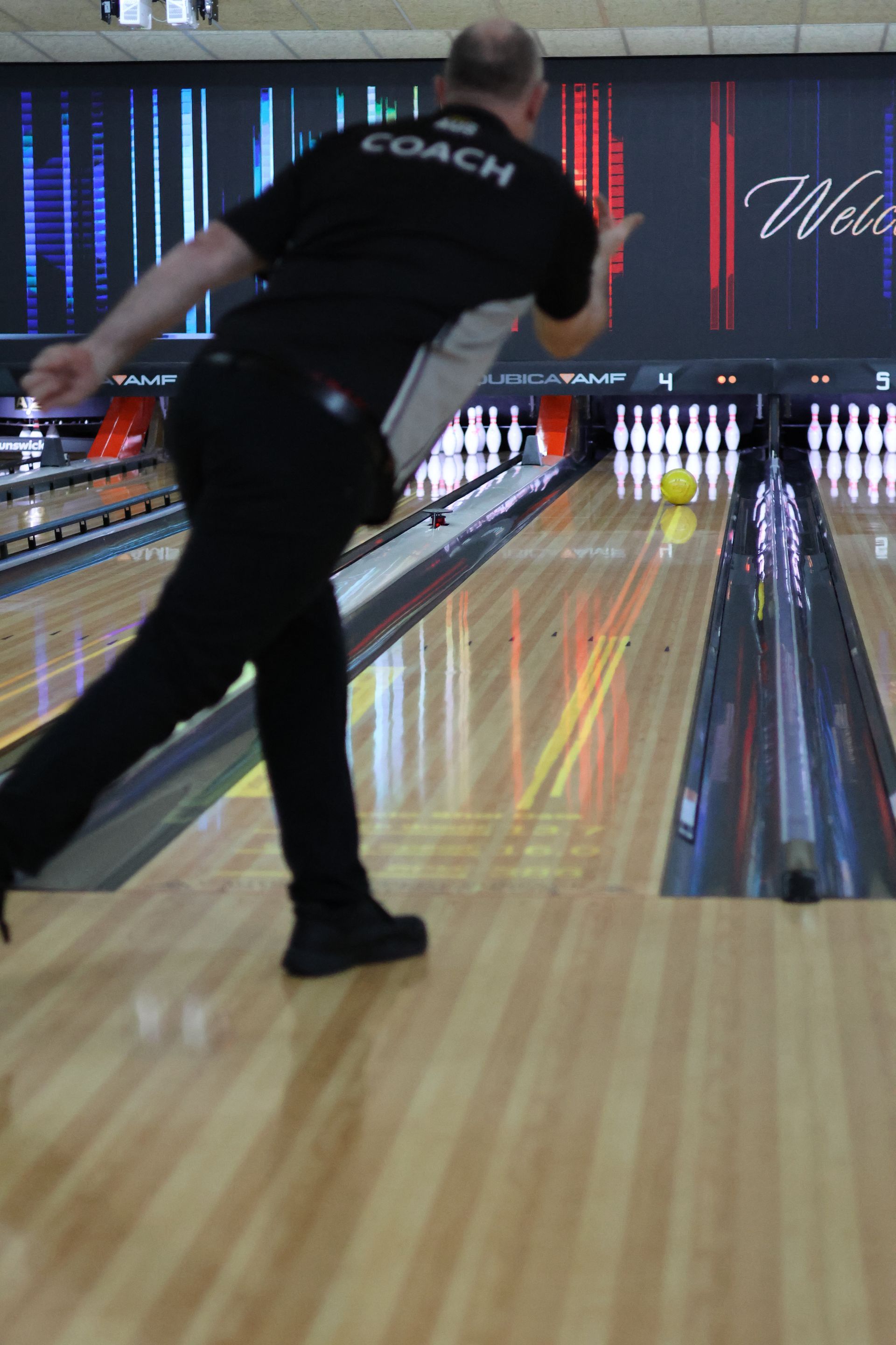 Bowler in Black Shirt Releases a Ball on a Bowling Lane, With Pins Visible Ahead — Orange Tenpin Bowl in Orange, NSW