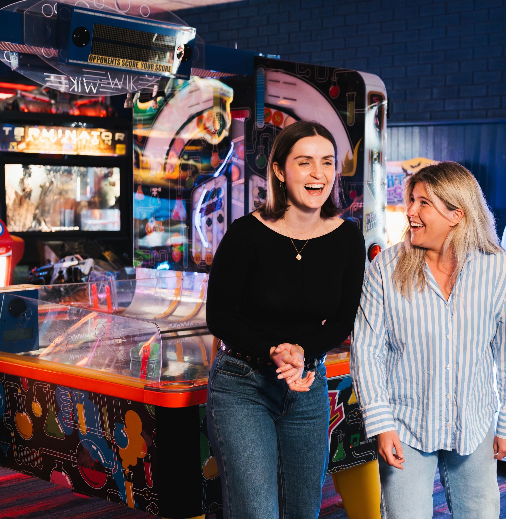 Two Women Laughing Beside a Arcade Game in a Neon-lit Arcade — Orange Tenpin Bowl in Orange, NSW