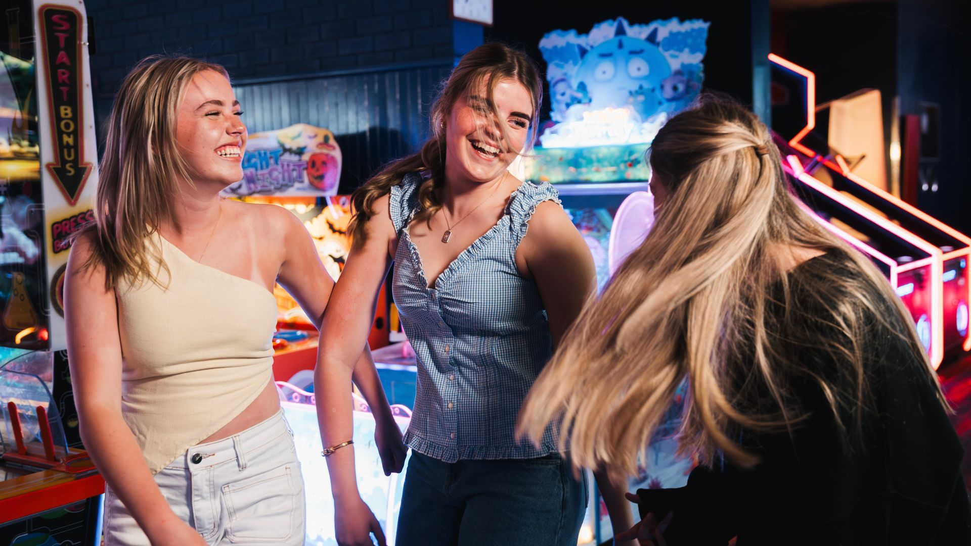 Three Friends Laughing Together in a Neon-lit Arcade With Game Machines in the Background — Orange Tenpin Bowl in Orange, NSW
