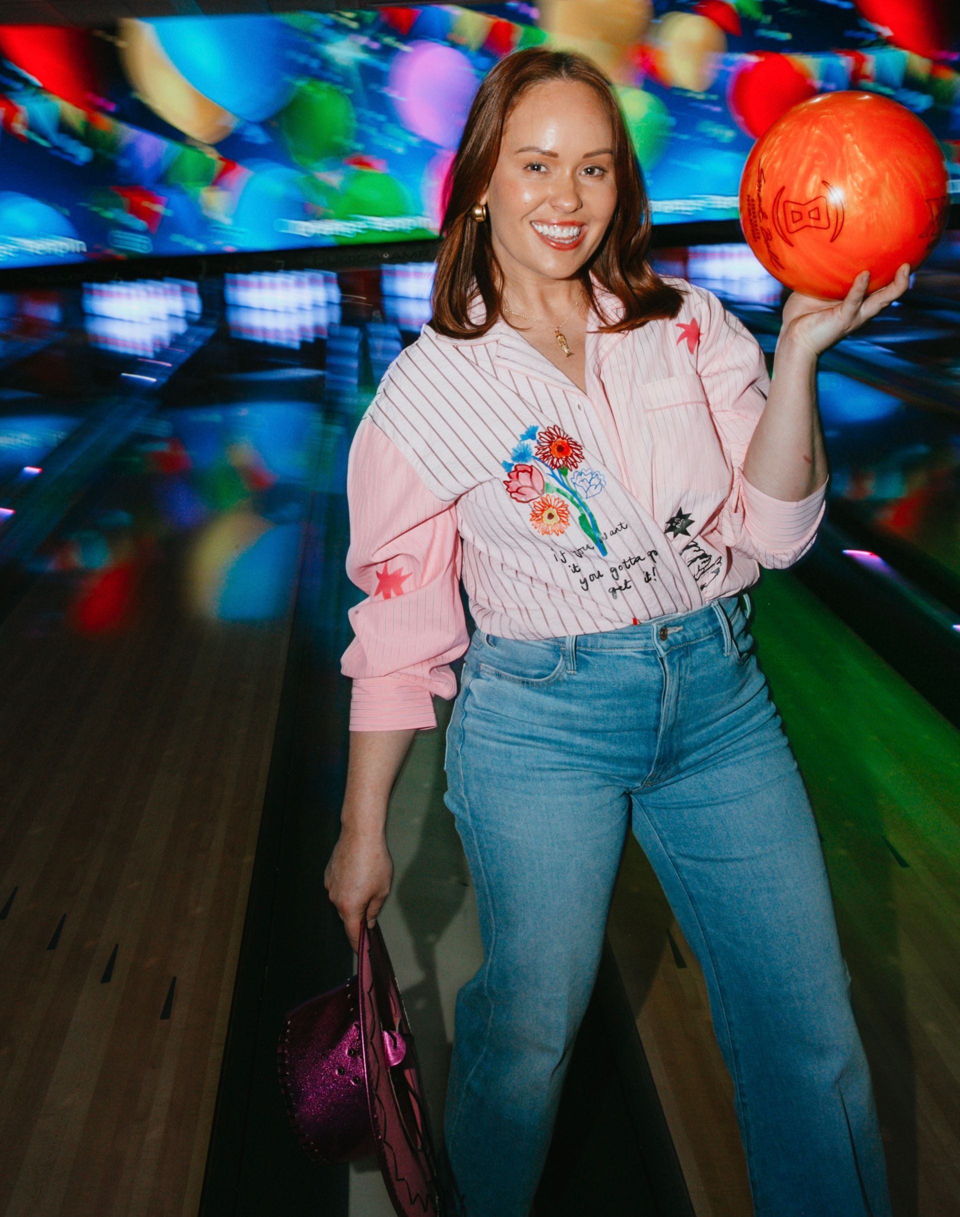 Woman Holding an Orange Bowling Ball and Bag, Smiling on a Bowling Alley Lane — Orange Tenpin Bowl in Orange, NSW