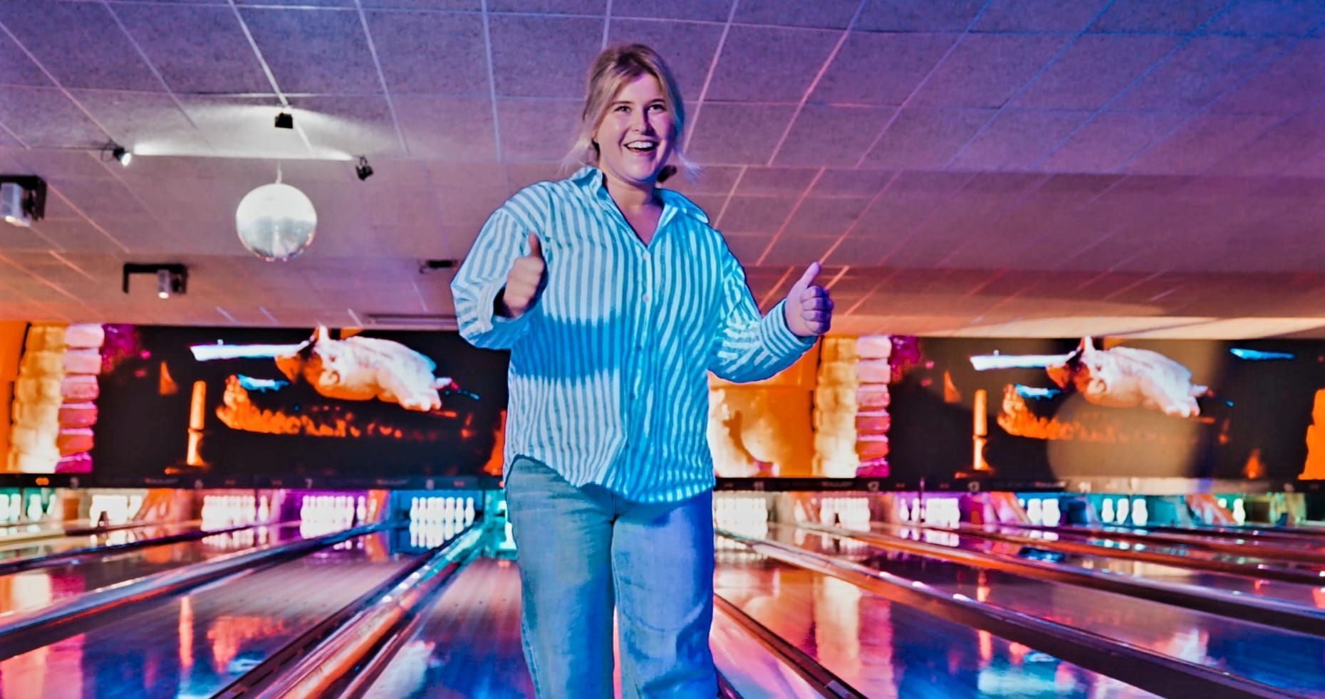Person Standing in a Brightly Lit Bowling Alley Between Lanes, Arms Raised and Smiling — Orange Tenpin Bowl in Orange, NSW