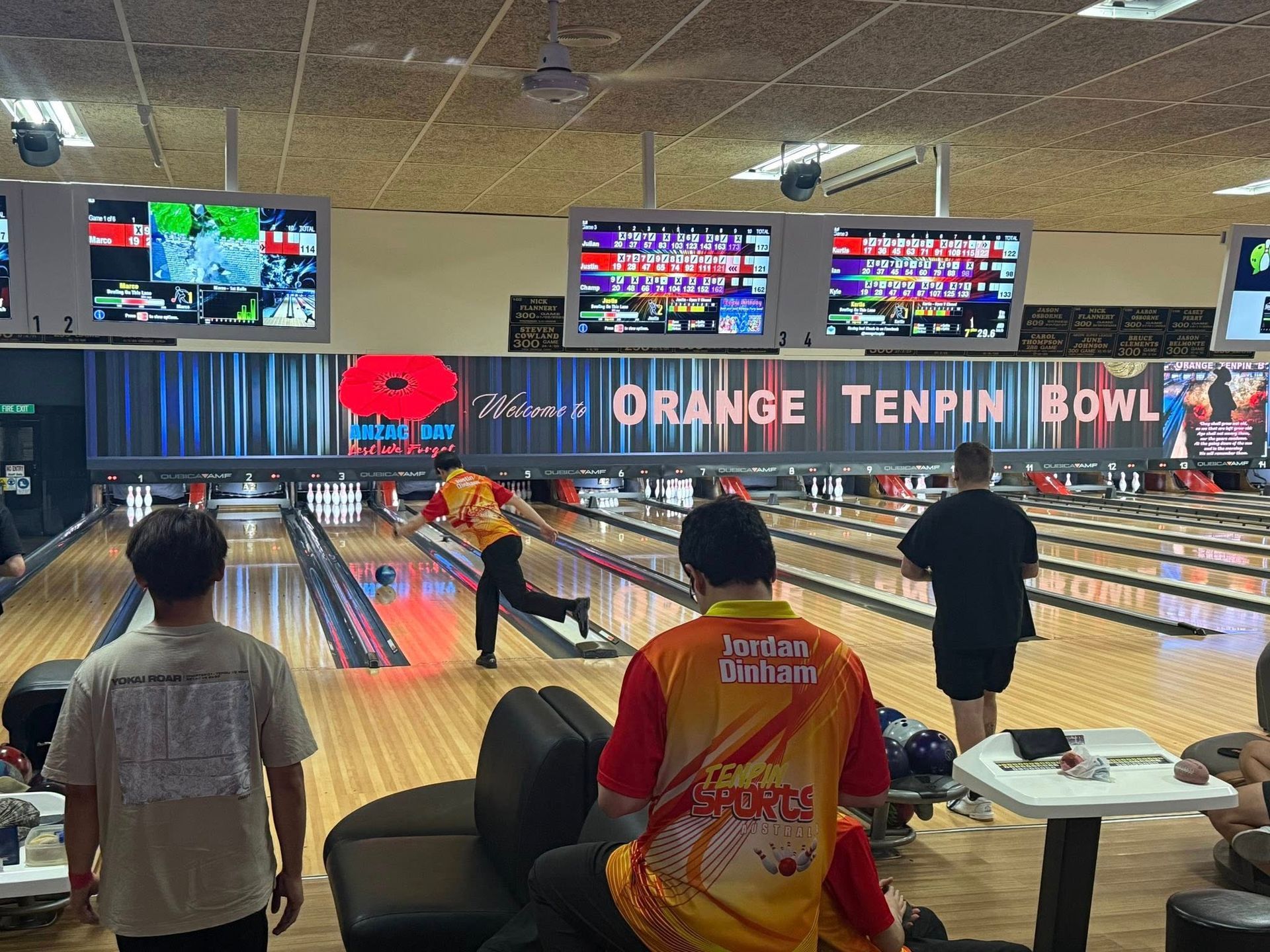 People Bowling in an Orange-lit Bowling Alley With Lanes, Screens, and Seated Onlookers — Orange Tenpin Bowl in Orange, NSW