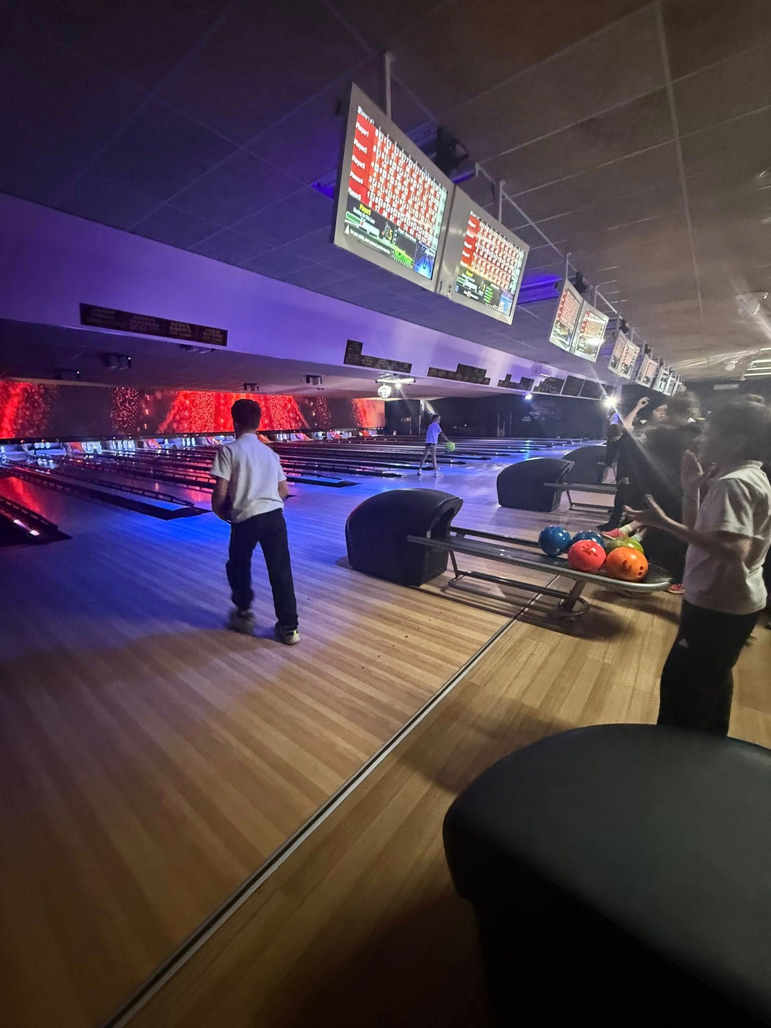 People Bowling in a Neon-lit Bowling Alley With Overhead Score Screens and Lanes — Orange Tenpin Bowl in Orange, NSW