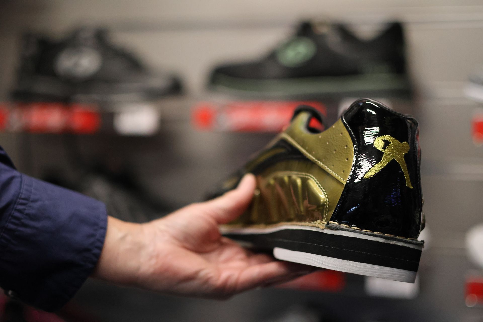 Hand Holding a Gold and Black Sneaker in a Shoe Store Display — Orange Tenpin Bowl in Orange, NSW