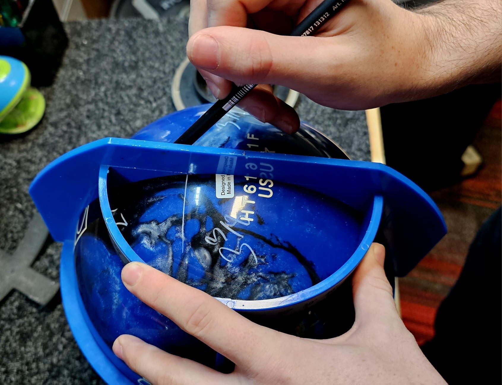 Hands Stirring a Blue Container With a Black Tool Over a Gray Carpet — Orange Tenpin Bowl in Orange, NSW