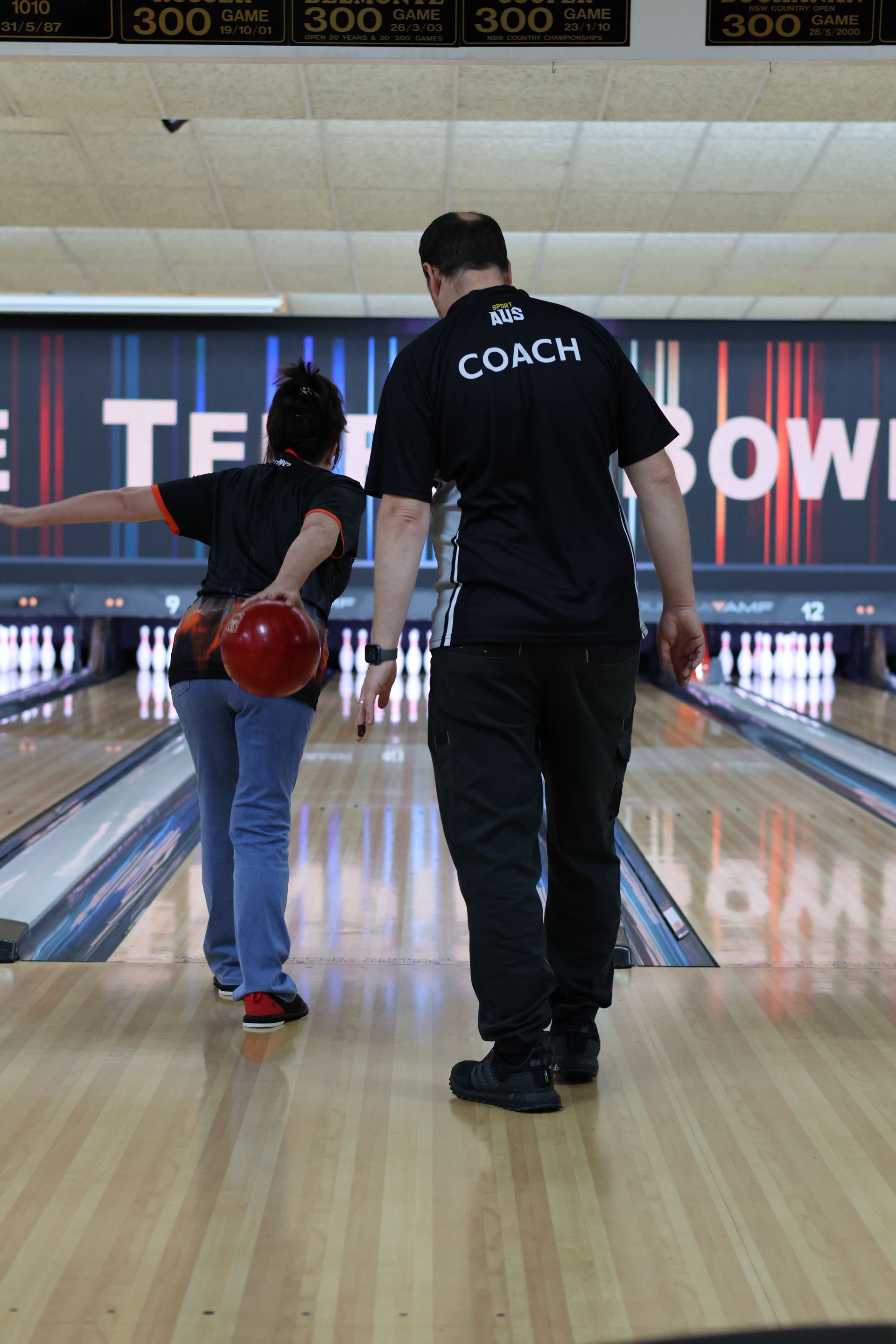 Bowling Coach Guiding a Child With a Red Ball Down a Bowling Lane — Orange Tenpin Bowl in Orange, NSW