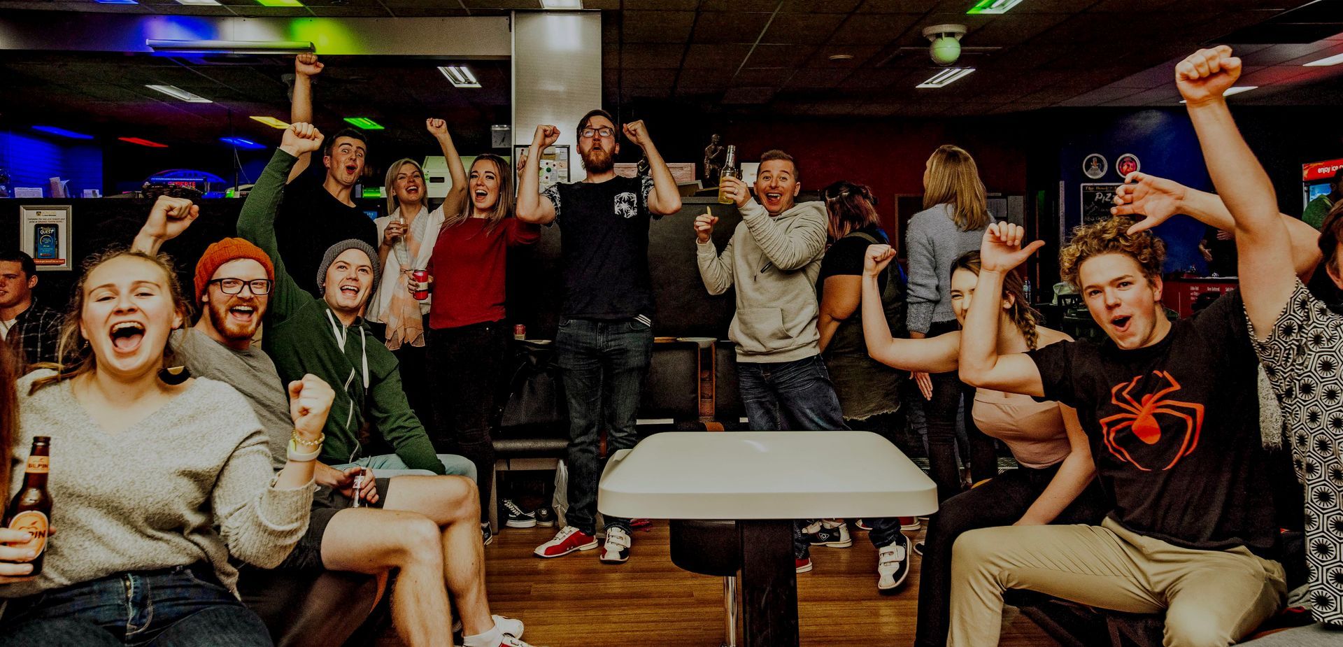 Cheering Group in a Lively Indoor Lounge, Raising Fists Around a Center Table — Orange Tenpin Bowl in Orange, NSW