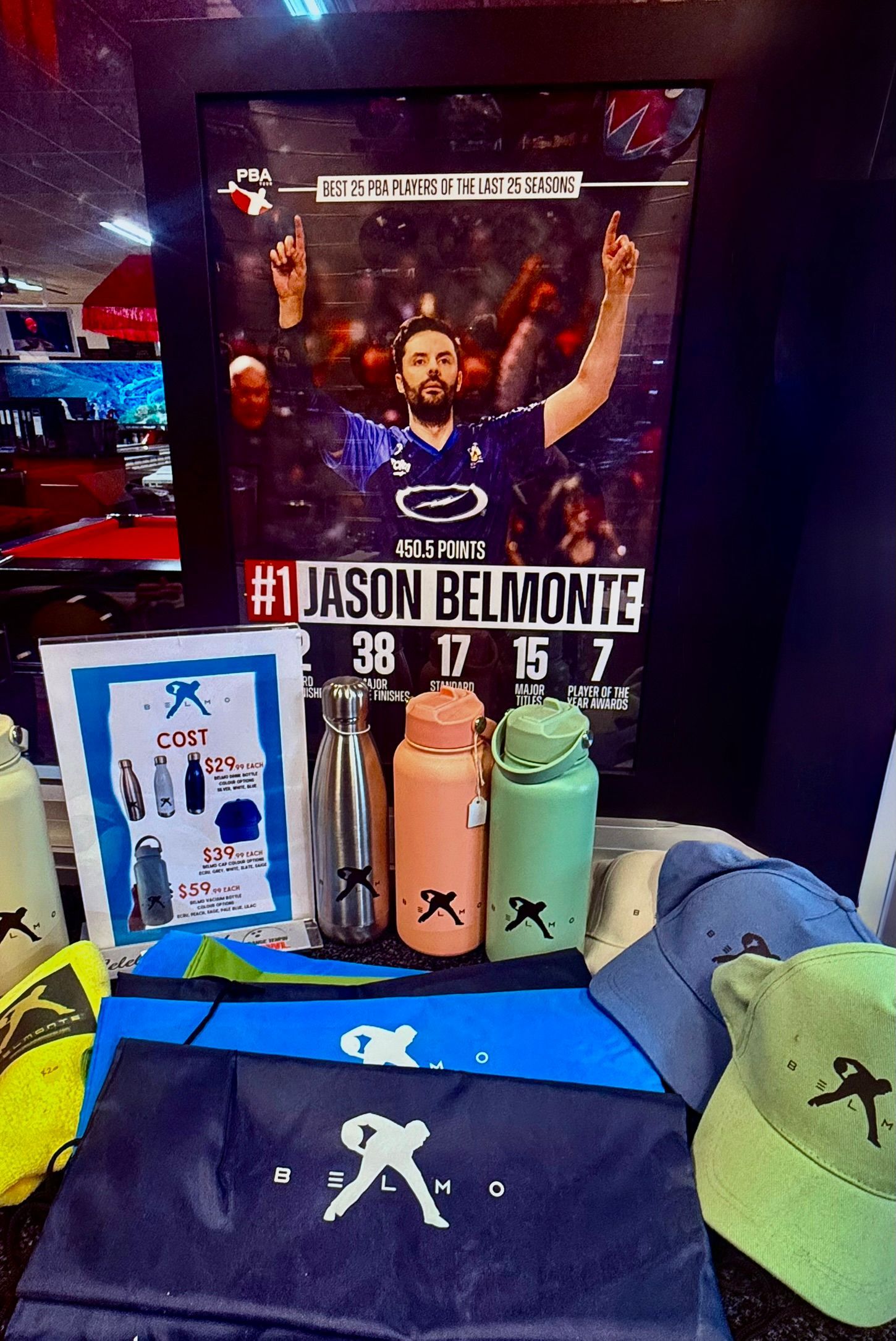 Jason Belmonte bowling display with trophies, shirts, water bottles, and a banner poster.
